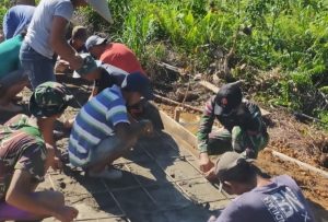 Anggota Satgas Yonif 144/JY Melaksanakan Gotong Royong Bersama Warga Pengecoran Makam di Perbatasan