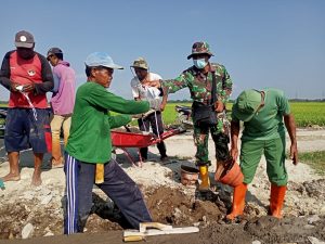 Babinsa Majasto, Intensif Pantau Perkembangan Sasaran Fisik TMMD Sekaligus Ingatkan Warga Tentang Prokes Dengan Membagikan Masker