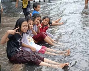 Bocah Asik Bermain Genangan Air, Ojol Dorong Motor, dan Warga Berharap Semoga Banjir Teratasi