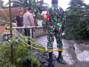 Kesiapan Babinsa Koramil Duren Sawit Cek Arus Air Sungai di Musim Penghujan